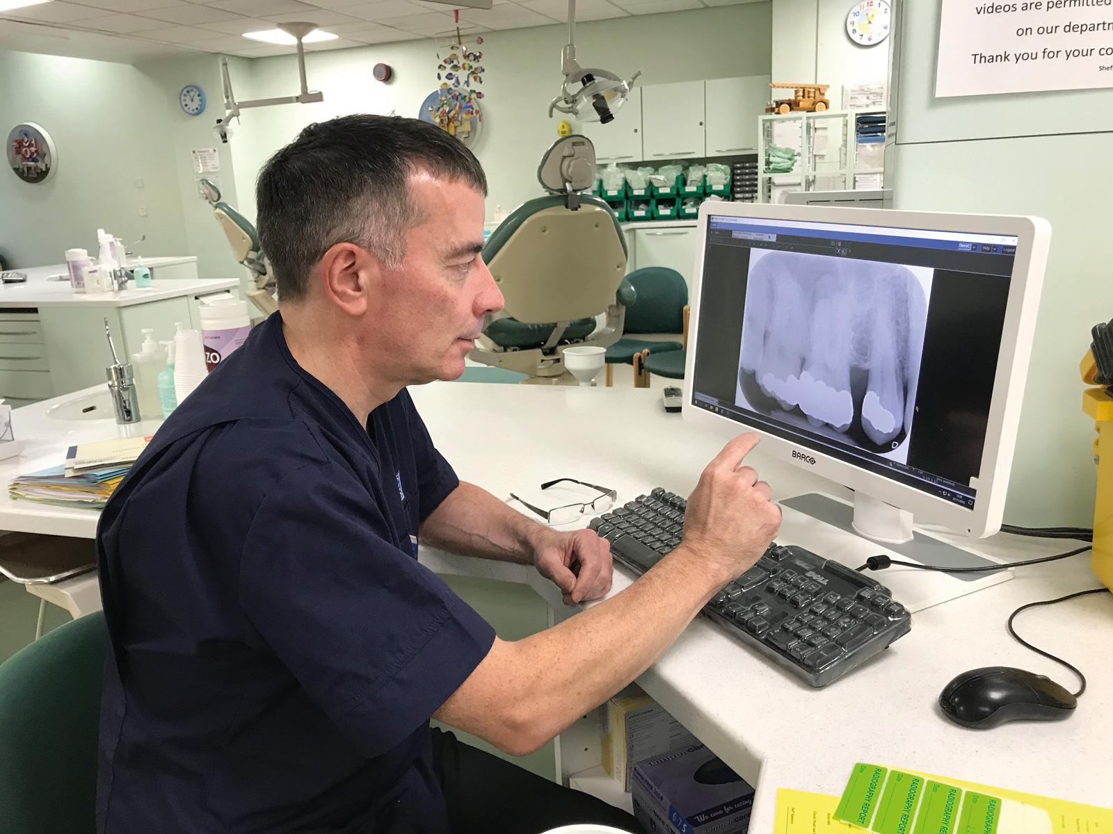 A dentist uses a computer to examine an x-ray