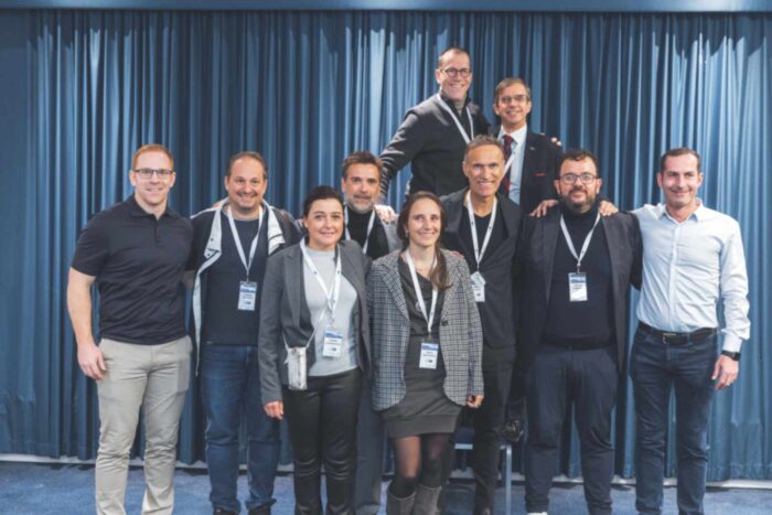 A group picture of the ten committee members standing in front of a curtain wall.