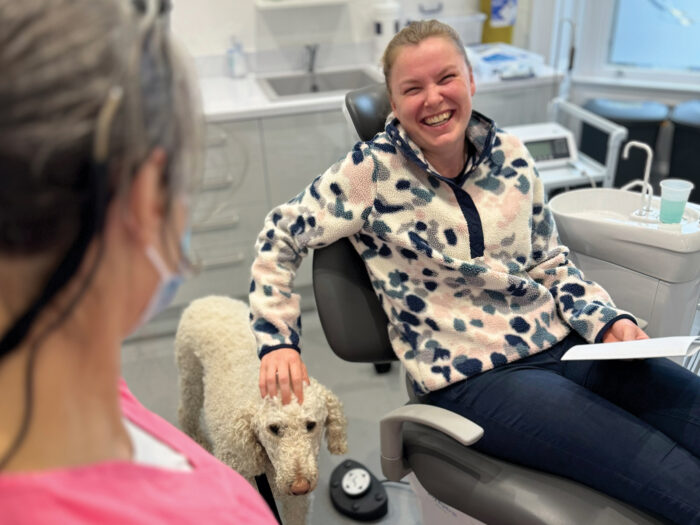 A dental patient looks very happy as she pets one of the therapy dogs while in the dentist's chair.